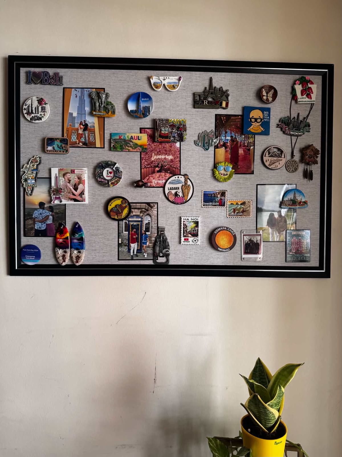 Large black frame travel magnet board featuring souvenir magnets and vacation photos from Bali, Paris, and Dubai
